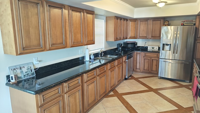 kitchen featuring appliances with stainless steel finishes, dark stone counters, a tray ceiling, light tile patterned floors, and ornamental molding