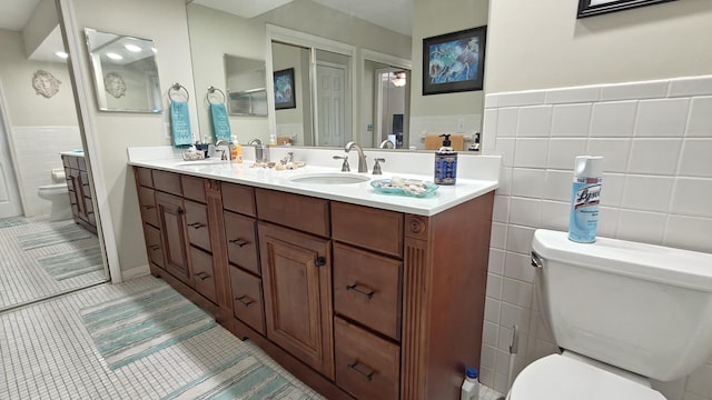 bathroom with tile patterned floors, vanity, tile walls, and toilet