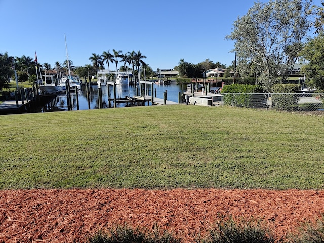 view of dock with a yard and a water view