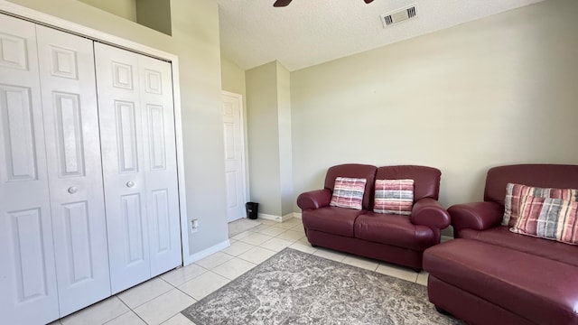 living room with light tile patterned floors, a textured ceiling, and ceiling fan