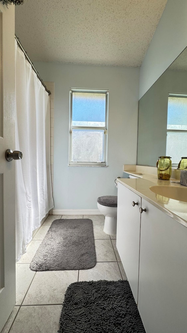 bathroom featuring tile patterned flooring, a textured ceiling, vanity, and toilet