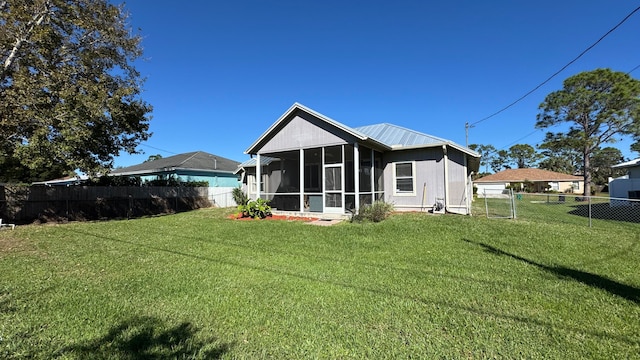 rear view of house with a sunroom and a lawn