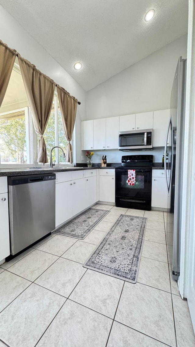 kitchen featuring a textured ceiling, white cabinetry, stainless steel appliances, and vaulted ceiling