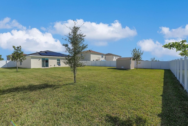 view of yard with a fenced backyard, an outdoor structure, and a storage unit