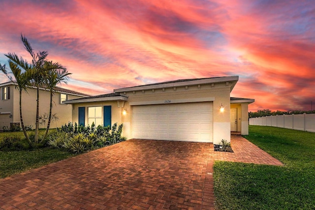 view of front facade with a garage, stucco siding, fence, decorative driveway, and a front yard