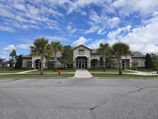 view of front of house with french doors, a front lawn, and stucco siding