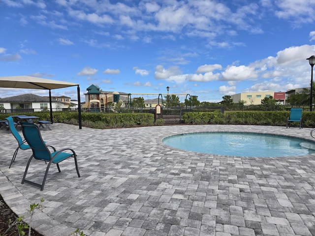 view of pool with playground community, a patio, fence, and a fenced in pool