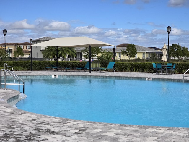 community pool with a patio area and fence