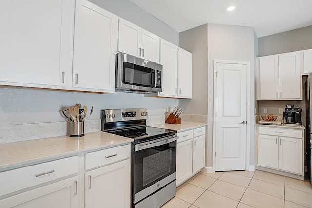 kitchen with light tile patterned floors, light stone countertops, stainless steel appliances, white cabinetry, and recessed lighting