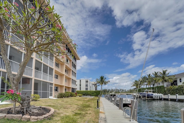 dock area featuring a water view, a lawn, and a balcony