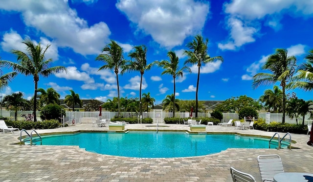 community pool with a patio area and fence