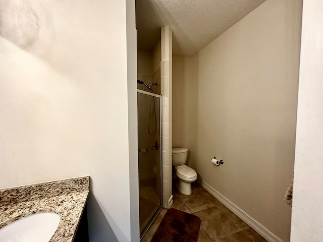 bathroom with vanity, tile patterned flooring, toilet, a textured ceiling, and walk in shower