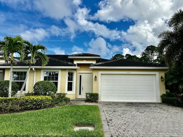 view of front of house featuring decorative driveway, an attached garage, and stucco siding