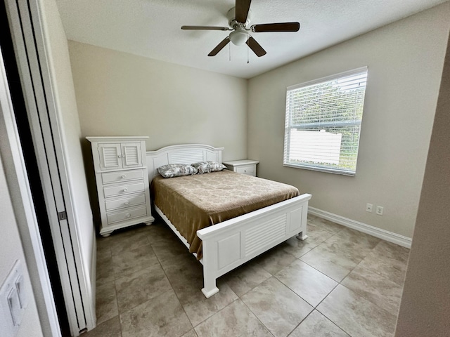 tiled bedroom featuring ceiling fan and a textured ceiling