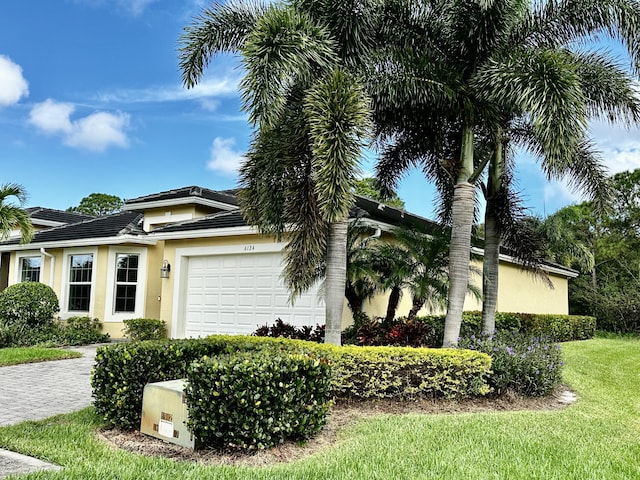 view of front of home with a tiled roof, an attached garage, and stucco siding