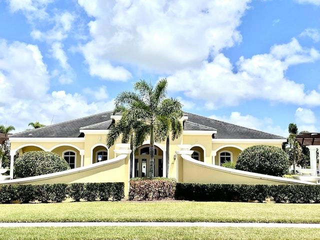 view of front facade featuring a tile roof, a front lawn, and stucco siding