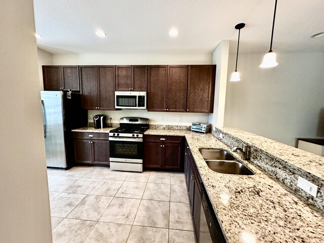 kitchen with dark brown cabinetry, stainless steel appliances, light stone counters, a textured ceiling, and light tile patterned flooring