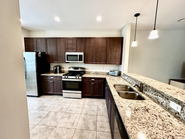 kitchen featuring appliances with stainless steel finishes, dark brown cabinets, a sink, and decorative light fixtures