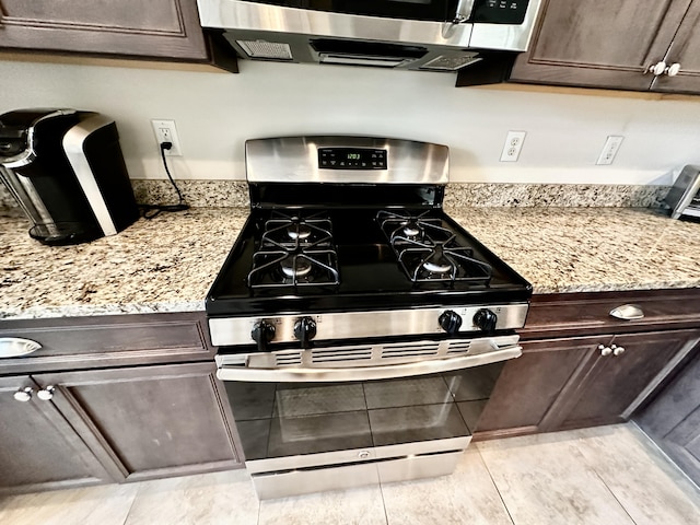 kitchen featuring stainless steel appliances, dark brown cabinets, and light stone countertops