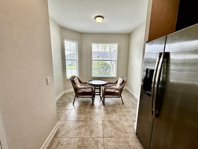 dining space with light tile patterned floors, baseboards, and a textured ceiling