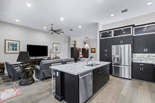 kitchen featuring light hardwood / wood-style flooring, sink, an island with sink, ceiling fan, and appliances with stainless steel finishes