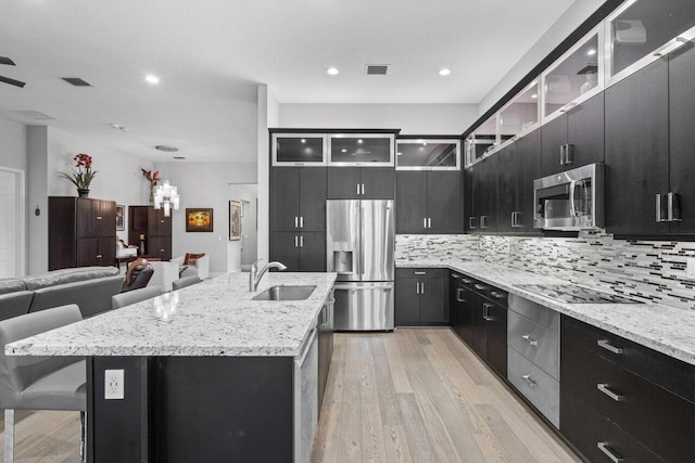 kitchen featuring light hardwood / wood-style flooring, sink, an island with sink, a breakfast bar, and appliances with stainless steel finishes