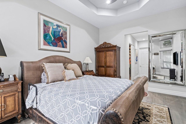 bedroom featuring hardwood / wood-style flooring, a tray ceiling, and a closet