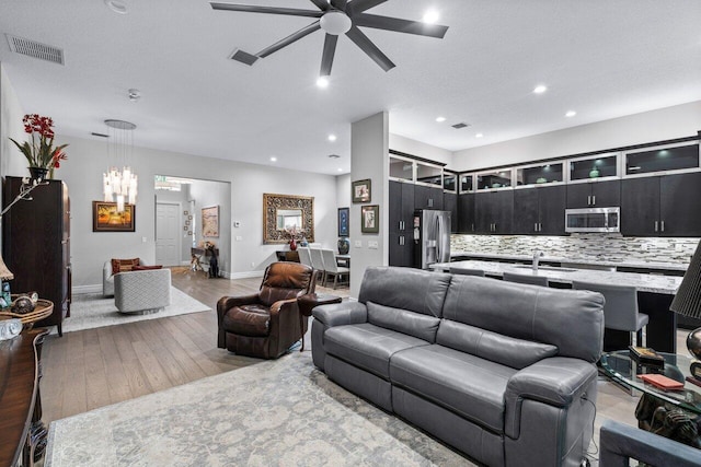 living room featuring a textured ceiling, light hardwood / wood-style floors, sink, and ceiling fan