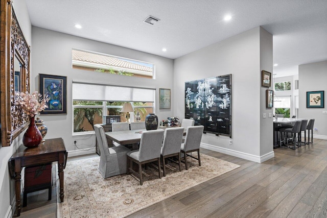 dining area with a wealth of natural light, wood-type flooring, and a textured ceiling