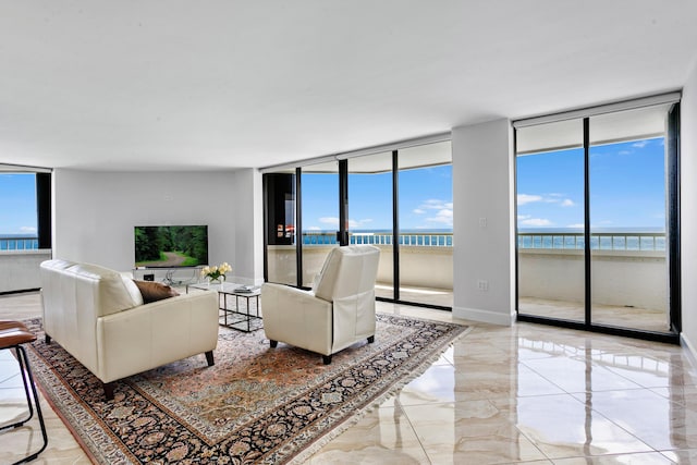 living room with a wealth of natural light, a water view, and a wall of windows