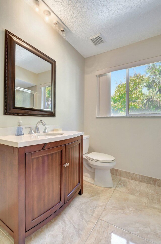 bathroom with vanity, a shower with door, tile patterned floors, toilet, and a textured ceiling