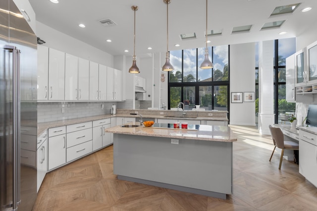 kitchen featuring high quality fridge, white cabinetry, pendant lighting, and plenty of natural light