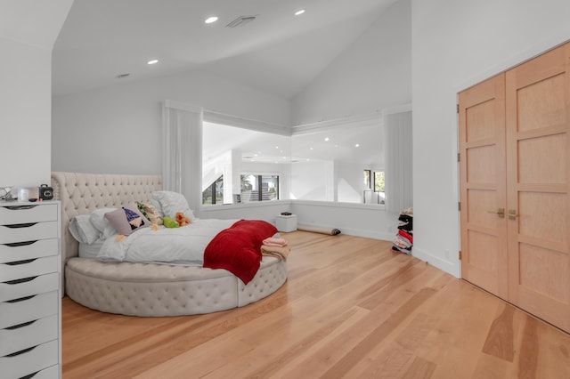 bedroom with wood-type flooring, multiple windows, and high vaulted ceiling