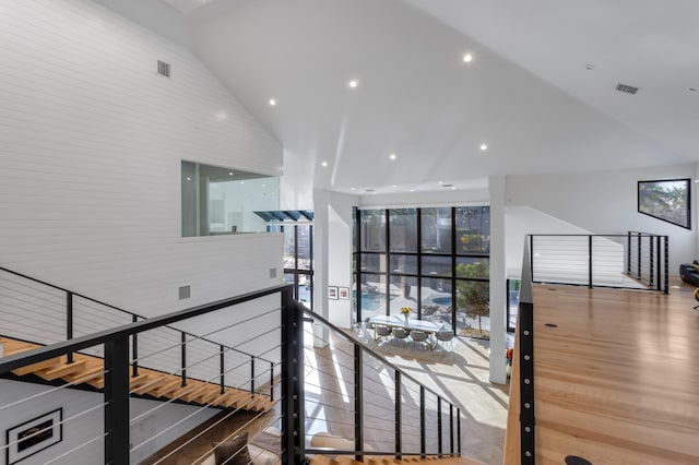 hall with hardwood / wood-style floors and high vaulted ceiling