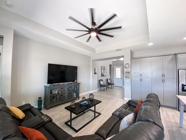 living room featuring a raised ceiling and ceiling fan