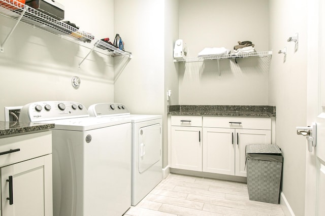 clothes washing area featuring cabinets and washer and clothes dryer