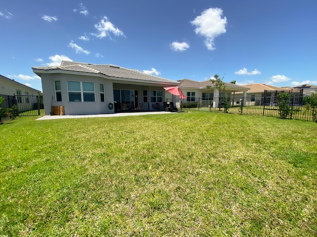 back of property with a lawn and a patio