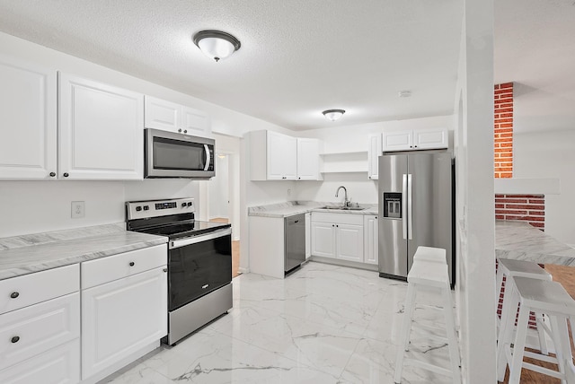 kitchen featuring white cabinets, appliances with stainless steel finishes, a textured ceiling, and sink