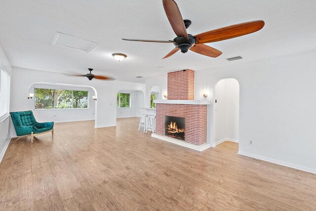 unfurnished living room featuring a fireplace, wood-type flooring, ceiling fan, and sink