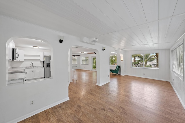 unfurnished living room with ceiling fan, light hardwood / wood-style floors, and sink