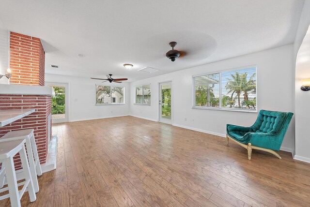 unfurnished living room with a fireplace, wood-type flooring, and ceiling fan