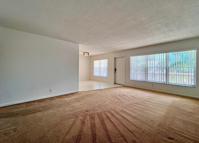 carpeted spare room featuring baseboards and a textured ceiling