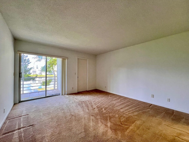 spare room with carpet floors, a textured ceiling, and baseboards