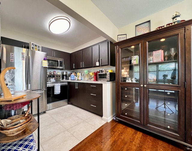 kitchen with light wood-type flooring, dark brown cabinetry, and stainless steel appliances