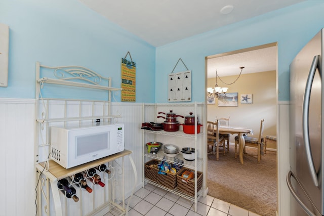 kitchen featuring refrigerator, an inviting chandelier, and light tile patterned flooring