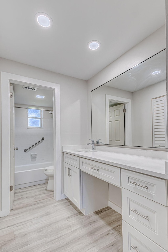 full bathroom with vanity, wood-type flooring, tiled shower / bath combo, and toilet