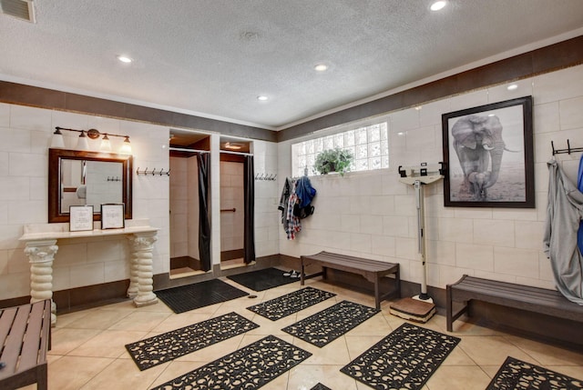 interior space featuring tile patterned flooring, a textured ceiling, and walk in shower