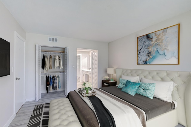 bedroom with a closet, light wood-style flooring, ensuite bathroom, baseboards, and visible vents