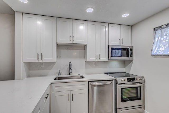 kitchen featuring appliances with stainless steel finishes, white cabinetry, and sink