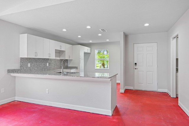 kitchen featuring white cabinetry, sink, light stone counters, backsplash, and kitchen peninsula